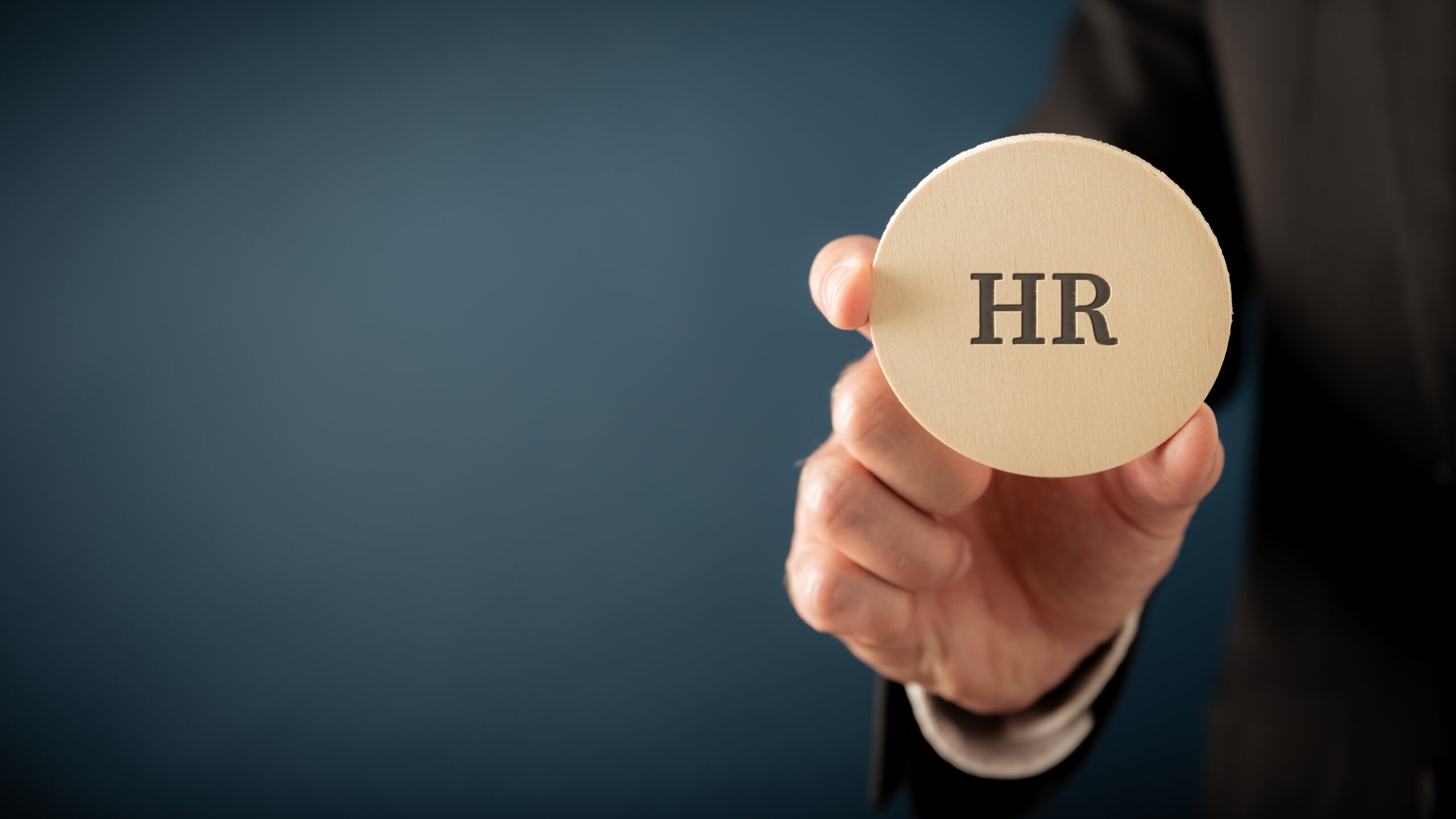 Businessman, an employer, holding a wooden cut circle wit an HR