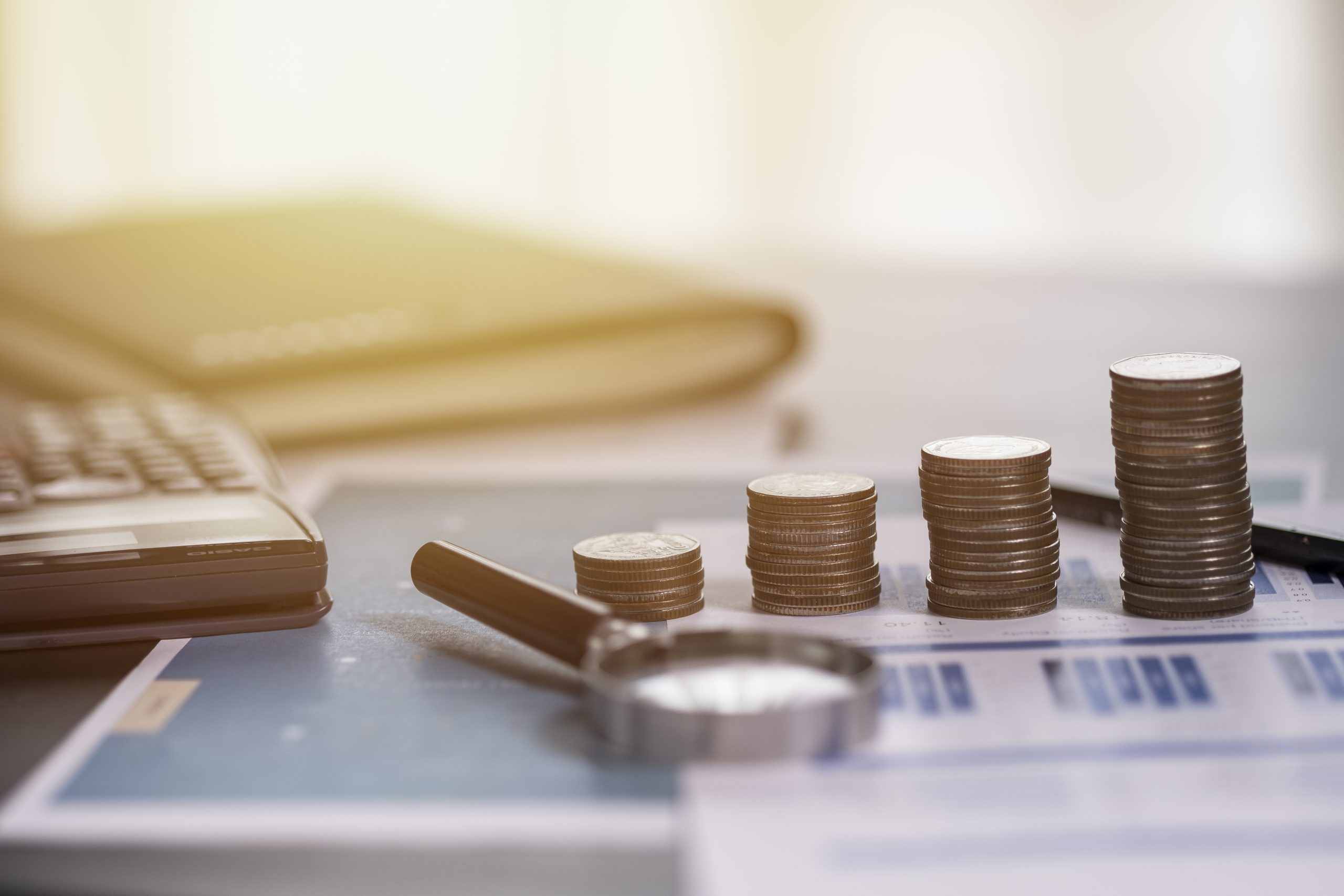 coins-stacking-financial-report-with-magnifier-glass-calculator-scaled